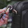 Antitheft water resistant Verona crossbody with locking straps. Demonstration of how to clasp the strap onto the bag's d-ring to secure it and deter pickpockets 