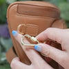 Anti theft bum bag in brown-gold, demonstration of locking strap clasps. Secure your bag with the clasps to deter theft