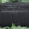 Anti-theft water resistant Bum Bag in black-gunmetal. Demonstration of water resistant microfiber faux leather with water running down the fabric