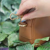 Myko crossbody with zipper clasps. Demonstration of how to clasp the zipper pull clasp onto the bag's d-ring to secure it close and deter pickpockets 