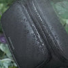 Anti-theft water resistant Bum bag in black-gunmetal. Demonstration of water resistant microfiber faux leather and YKK water resistant zipper with water running down the fabric