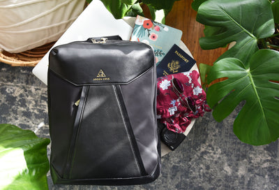 MB Packing Backpack Black Gold  modeled on table with passport and camera